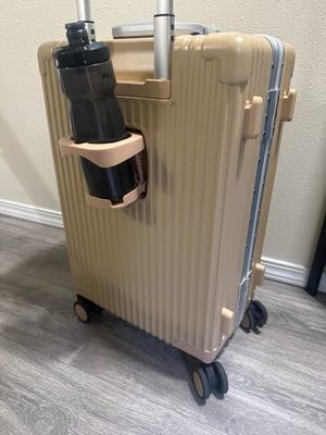 Customer-uploaded image. Click to see more details. The image represents: A beige hard-shell rolling suitcase with four wheels, featuring an attached black cup holder and a metal telescoping handle on top.