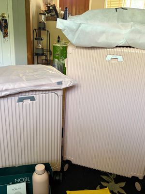 Customer-uploaded image. Click to see more details. The image represents: Two pink hard-shell suitcases with protective covers in a home interior.